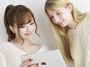 日本人女性と外国人女性がタブレットを見ながら会話している