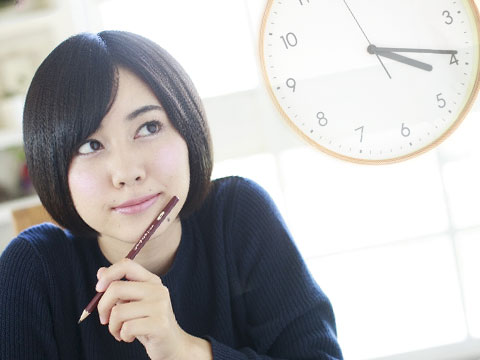 時計を思い浮かべ時制を気にしながら英語の勉強をしている女性