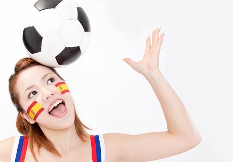 サッカーボールを頭にのっけて楽しむ頬にスペイン国旗をペイントした女性
